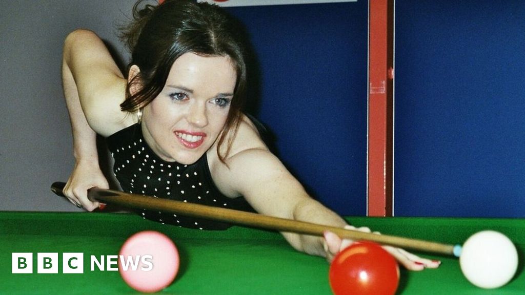 Older English blond plays with her cookie on a pool table