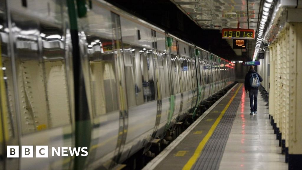 A man walks alongside a stationary train on an empty platform at London Victoria