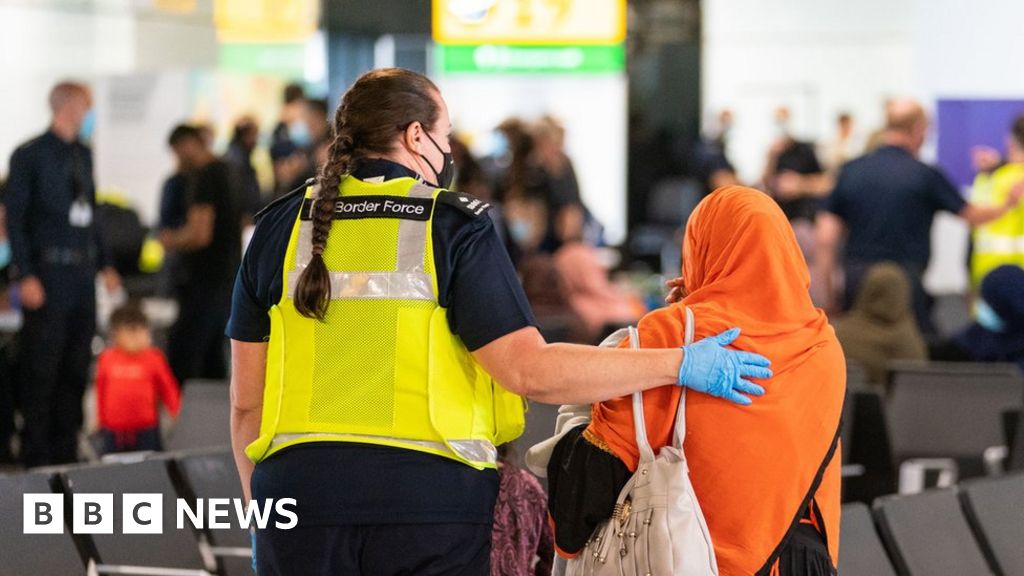 UK Border Force staff assisting a female evacuee as refugees arrive from Afghanistan at Heathrow Airport, August 26th 2021