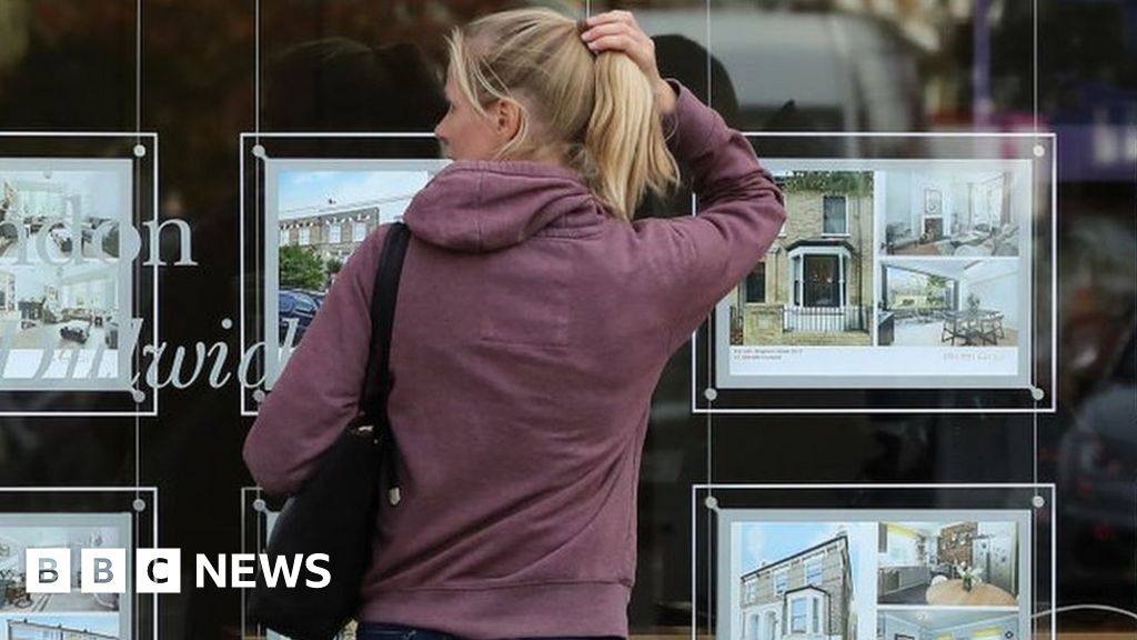 Woman looks in estate agent wndow