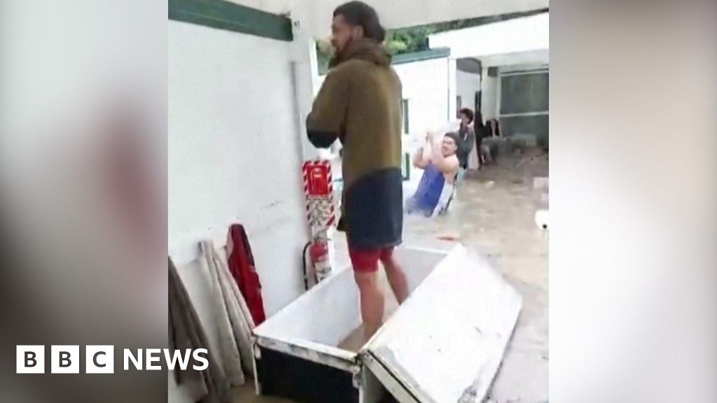 Cyclone Gabrielle: Workers use fridge and mattress to navigate floods