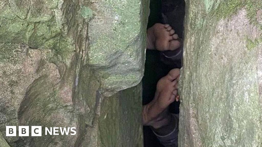 Woman reaching for phone gets stuck  upside down in boulders