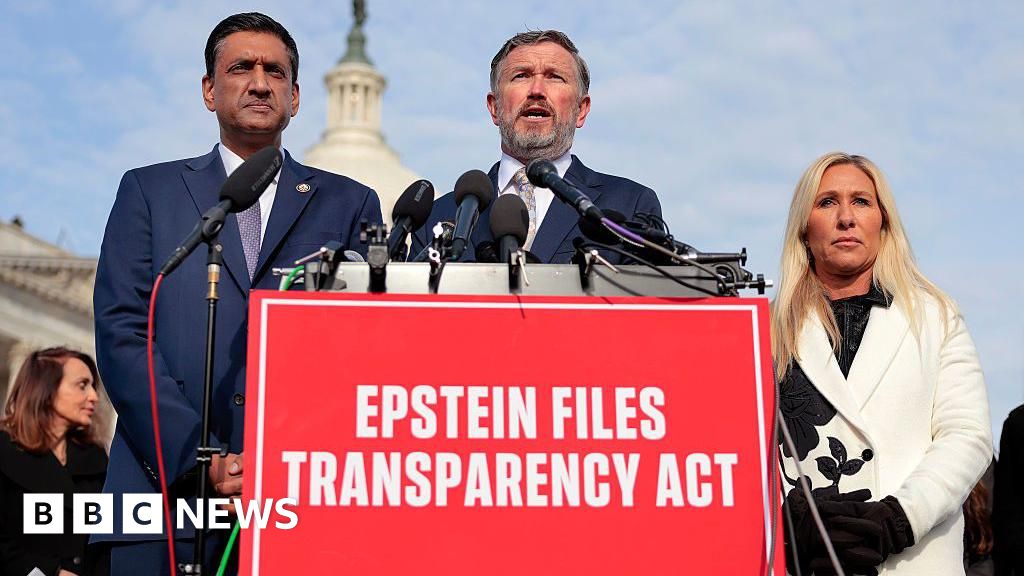 Representatives Ro Khanna, Thomas Massie and Marjorie Taylor Greene speak behind a red sign that reads "Epstein Files Transparency Act"