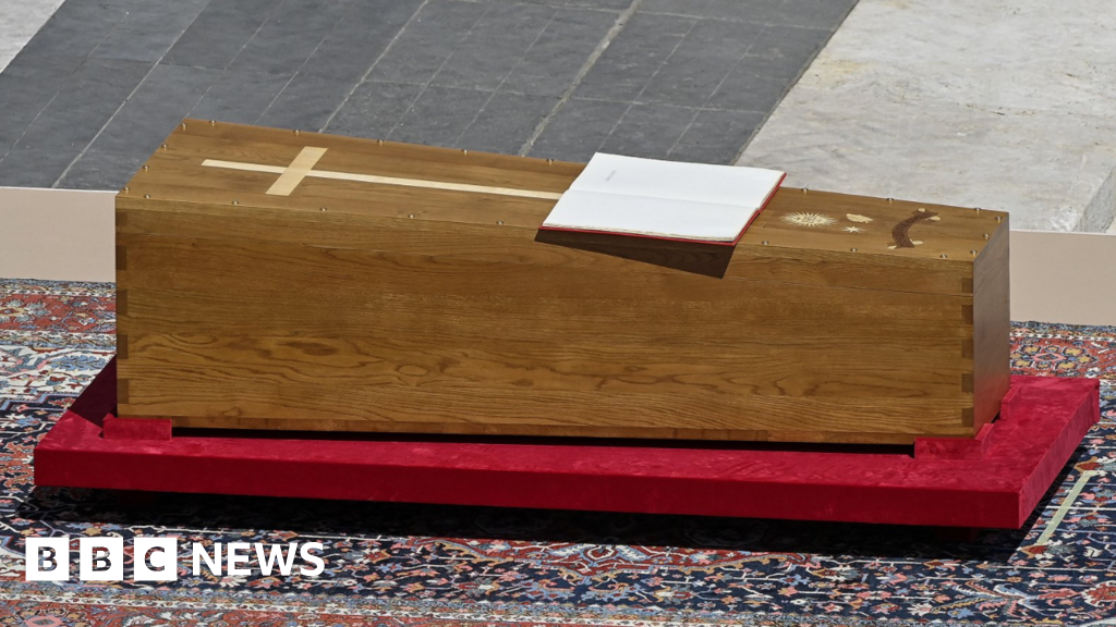 A simple wooden coffin amidst extraordinary opulence