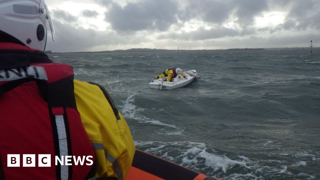 Three rescued in Poole Harbour as dinghy capsizes - BBC News