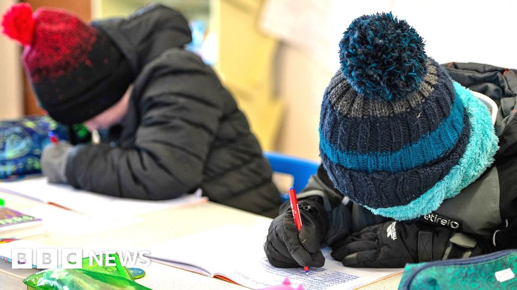 Children wear coats, hats and gloves in their classroom