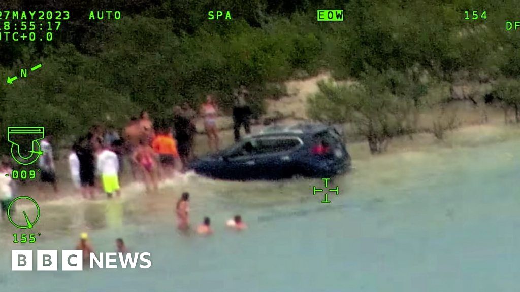 Driver speeds through crowded beach into water