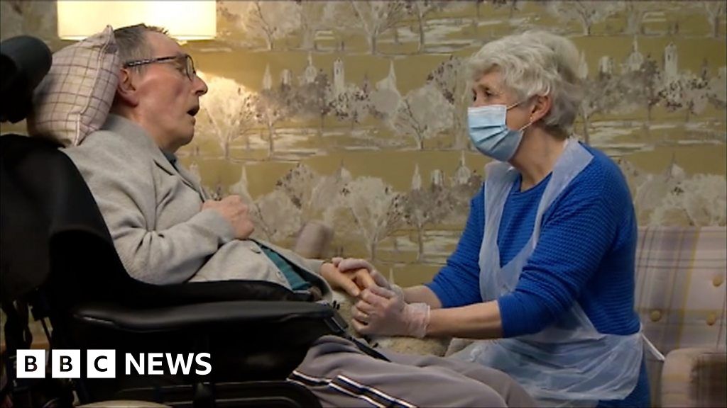 Covid Wife holds care home husband’s hand for first time in a year
