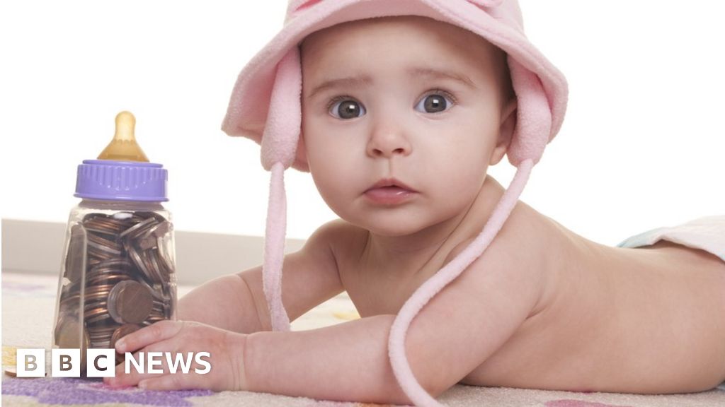 Photo of a baby holding a bottle full of coins