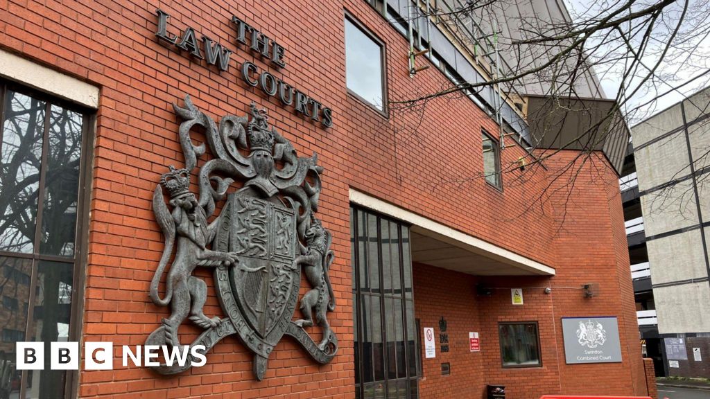 The exterior frontage of Swindon Crown Court, with red bricks and a large legal insignia 