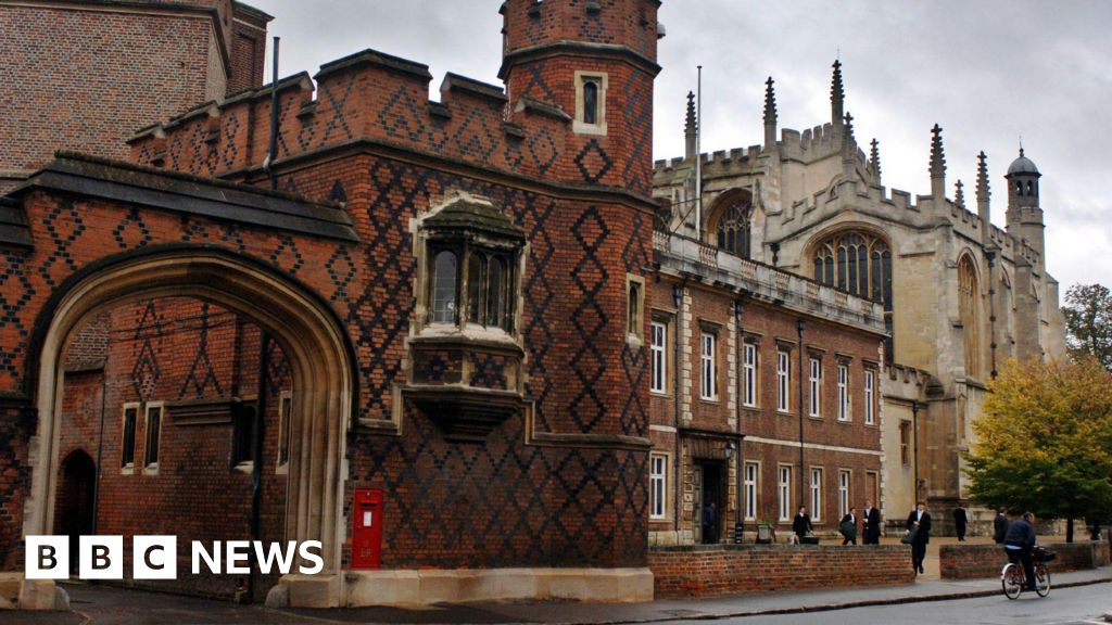 Eton College. A photograph of the redbrick school taken from across the road. A large archway is shown leading into the building on the right. Smartly dressed people are standing in a yard outside the adjacent building.