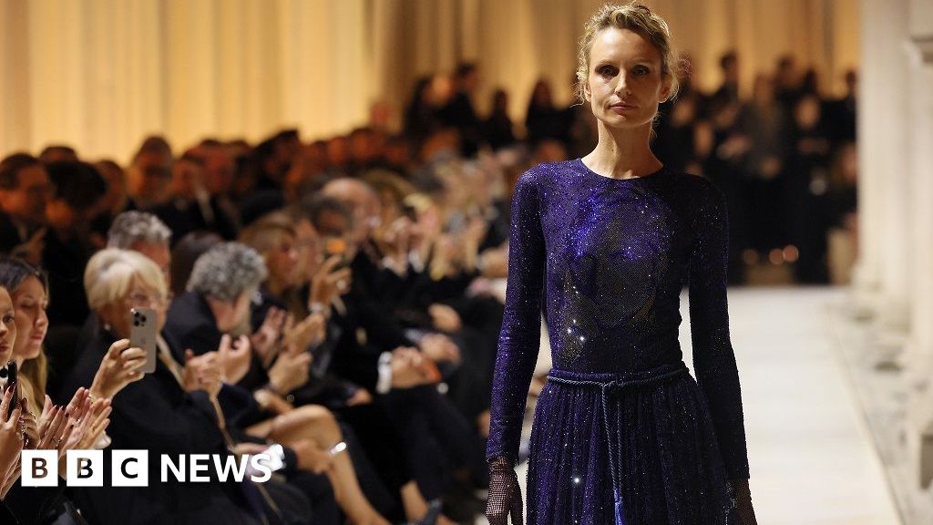 Model Agnese Zogla walking the runway in a dress featuring Giorgio Armani's face
