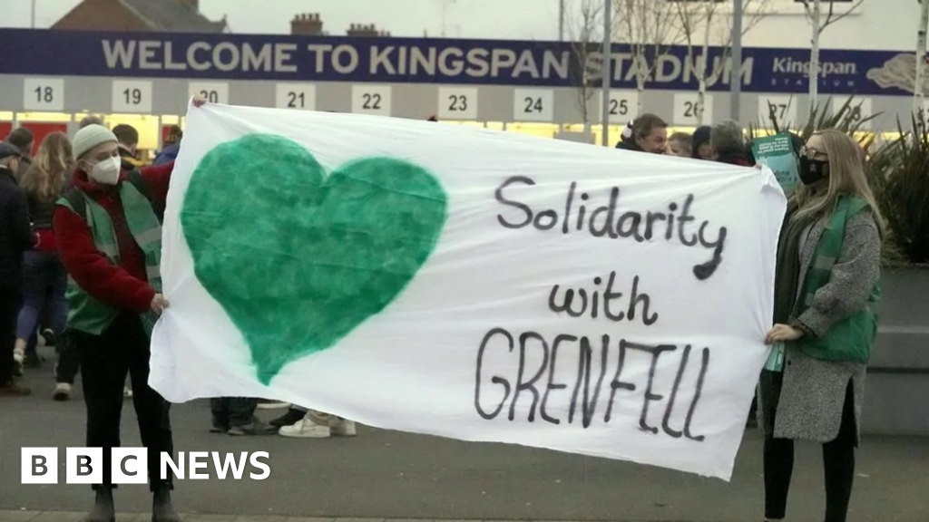 Protesters outside Kingspan stadium holding a solidarity with grenfell banner
