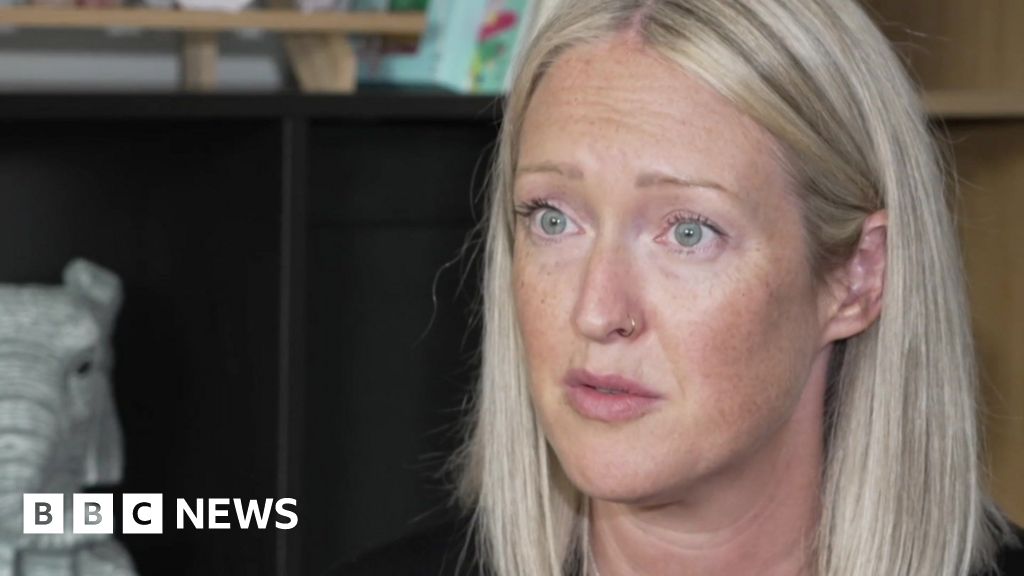 Esther Ghey with long blonde hair and green eyes and gold nose ring sitting in a room with a black cabinet behind her.