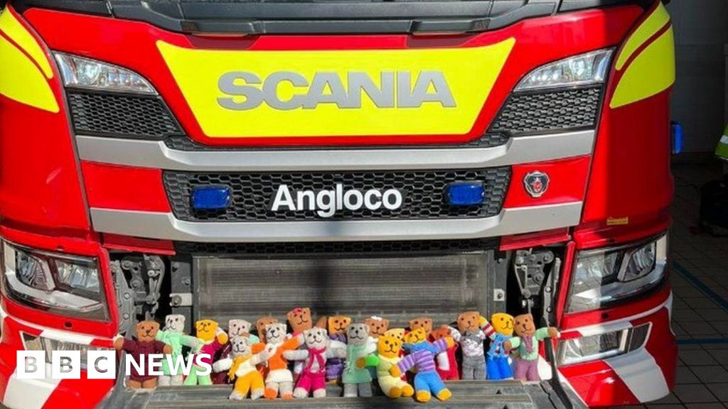 Rows of colourful knitted small teddy bears line the front of a fire engine