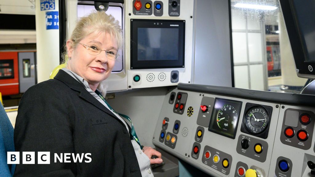 Leigh Santamaria sat in the drivers seat on a train. She is wearing a black blazer and looking directly at the camera.