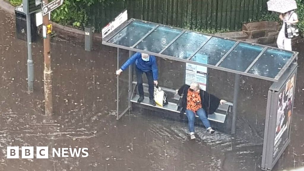 couple stuck in floodwater at bus stop