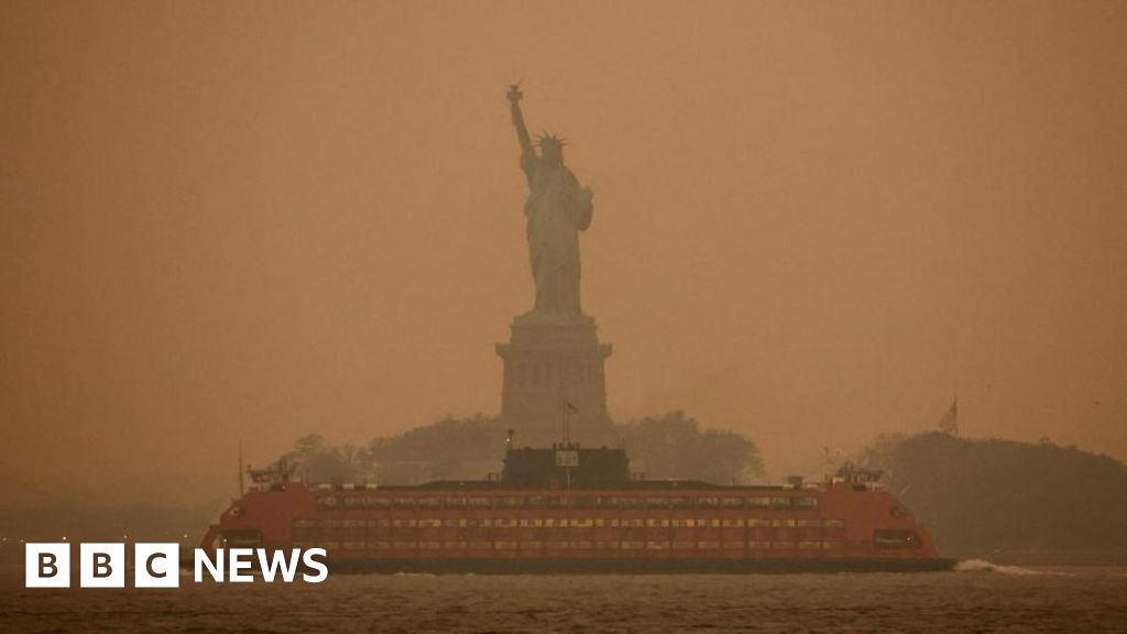 Statue of Liberty shrouded in orange haze from wildfire