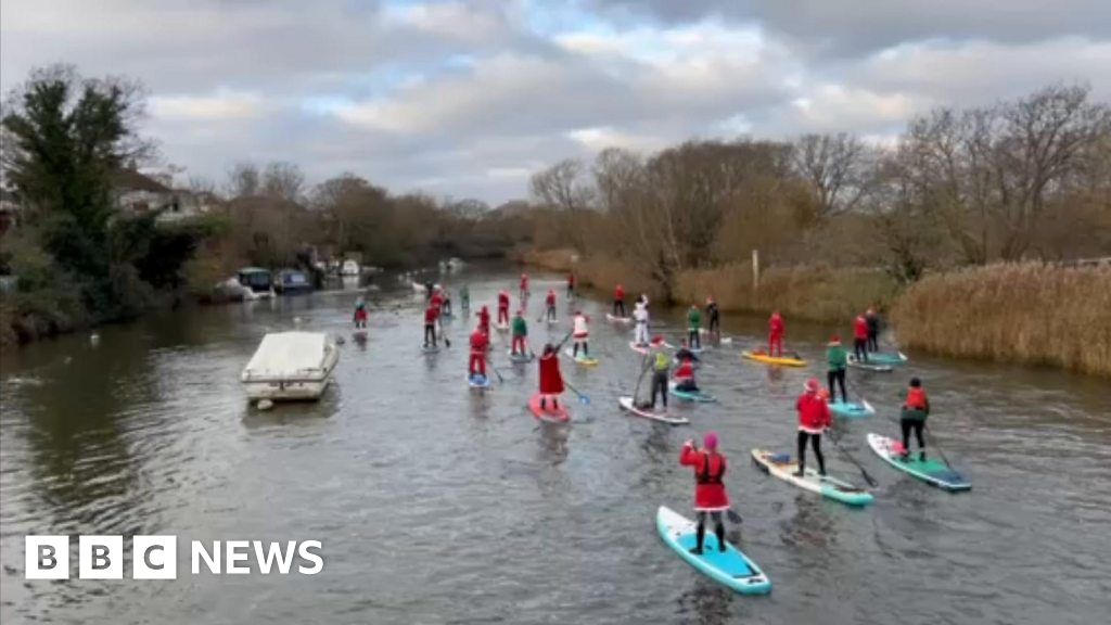 Paddleboarding Santas drift down the River Stour in Dorset 