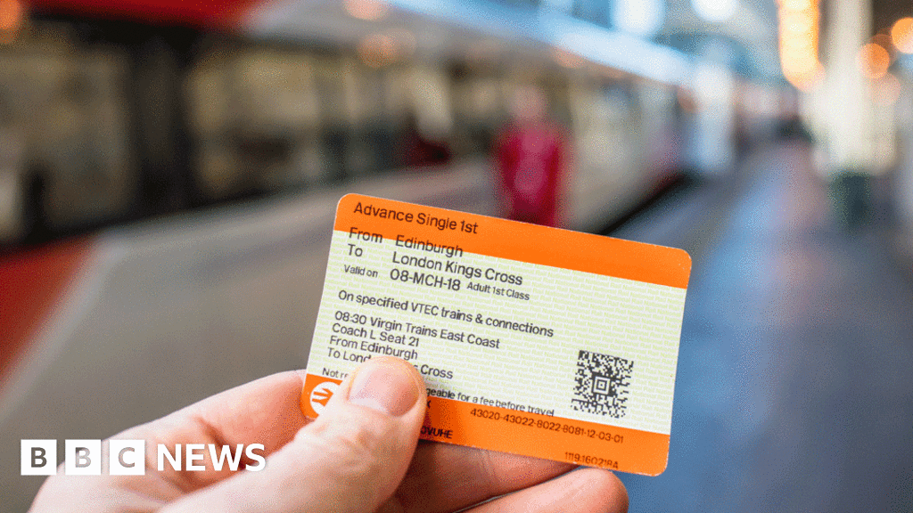 A person holding up a train ticket with train in background