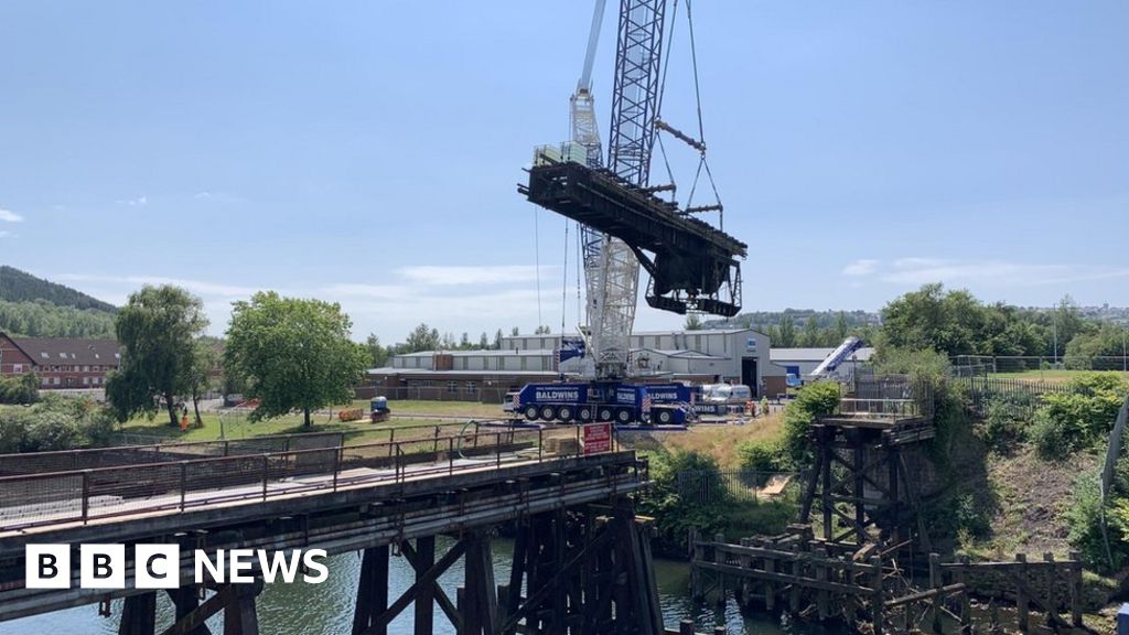 Crane lifts bridge section from its footings