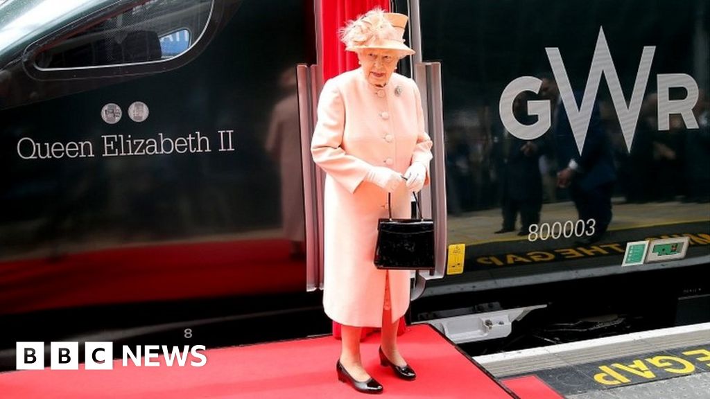 The Queen looks at her name on a train