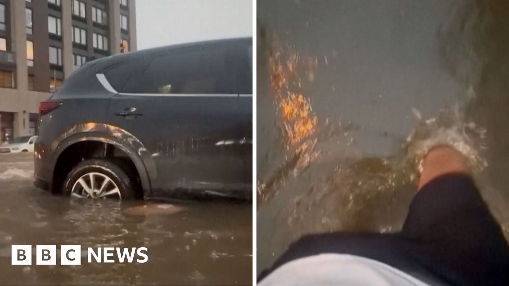 Residents wade through flood waters and submerged cars in New York City