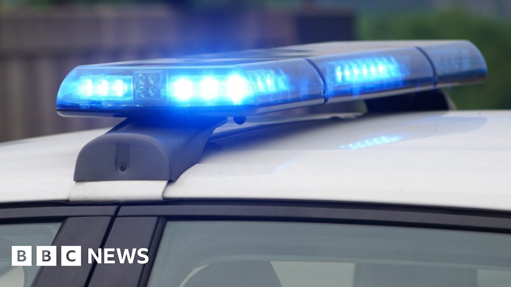 A close-up of the light bars on a police car, flashing a bright blue light. The background is blurred