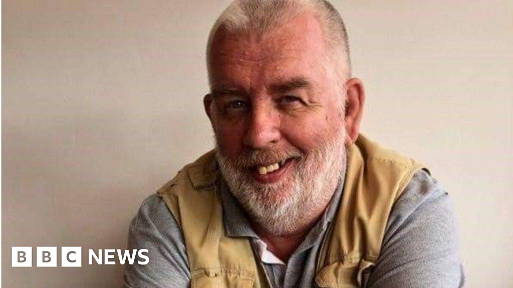 Andrew Rowland-Stuart, who died at his home on 27 May, smiling, wearing a grey t-shirt and grey waistcoat