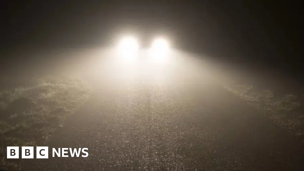 Bright headlights shining through a dark and gloomy night