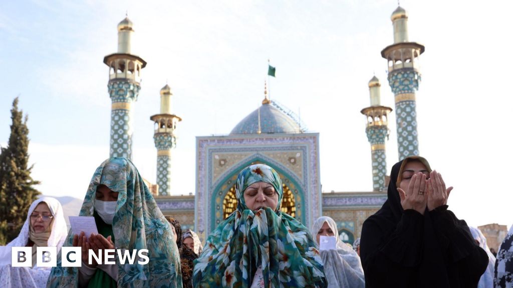 Iranian women praying at the Shrine of Panj Tan, in Tehran. The Shrine has four tall towers that are covered in a beautiful and intricate pattern that is blue and white.