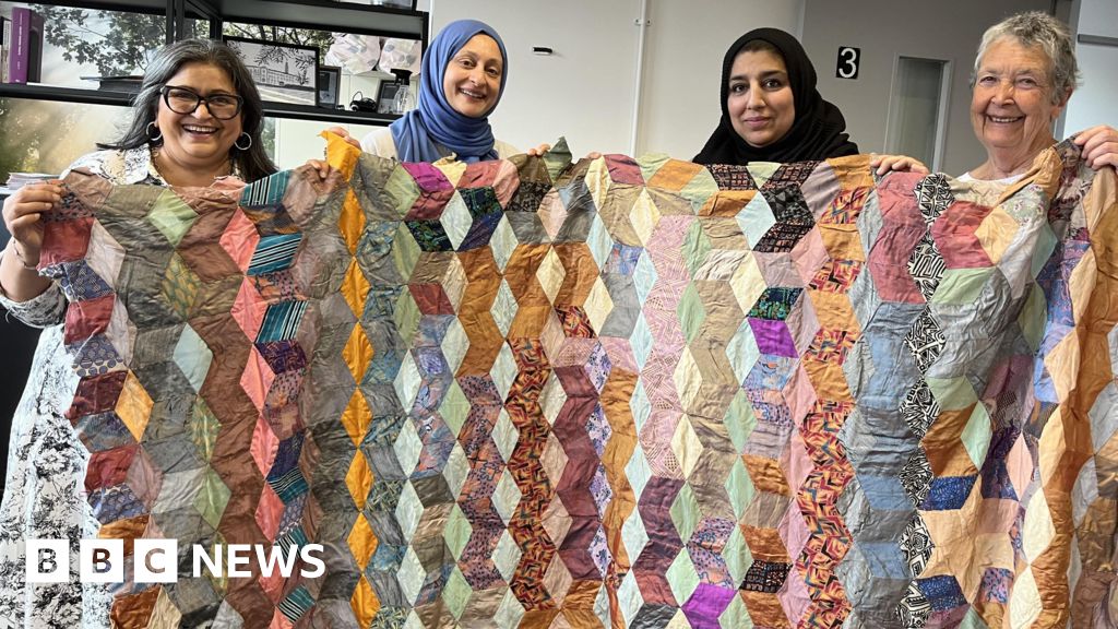Tanu Patel and members of the Sewcialise group examining a Victorian quilt
