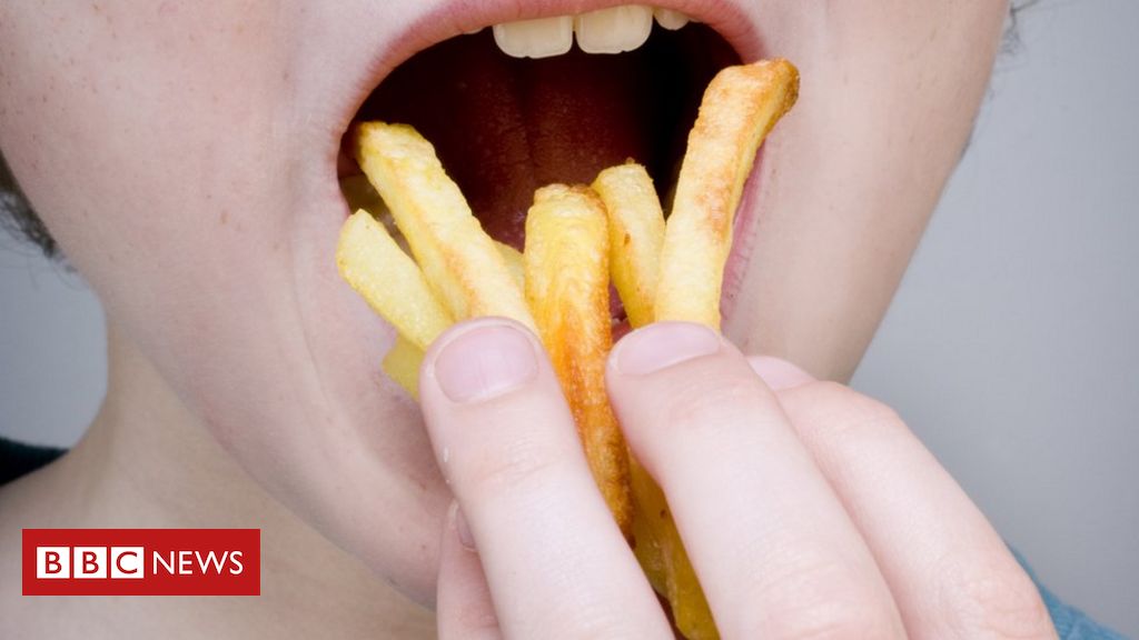 Jovem macho comendo batata frita enquanto espera o filme terminar na  superfície branca