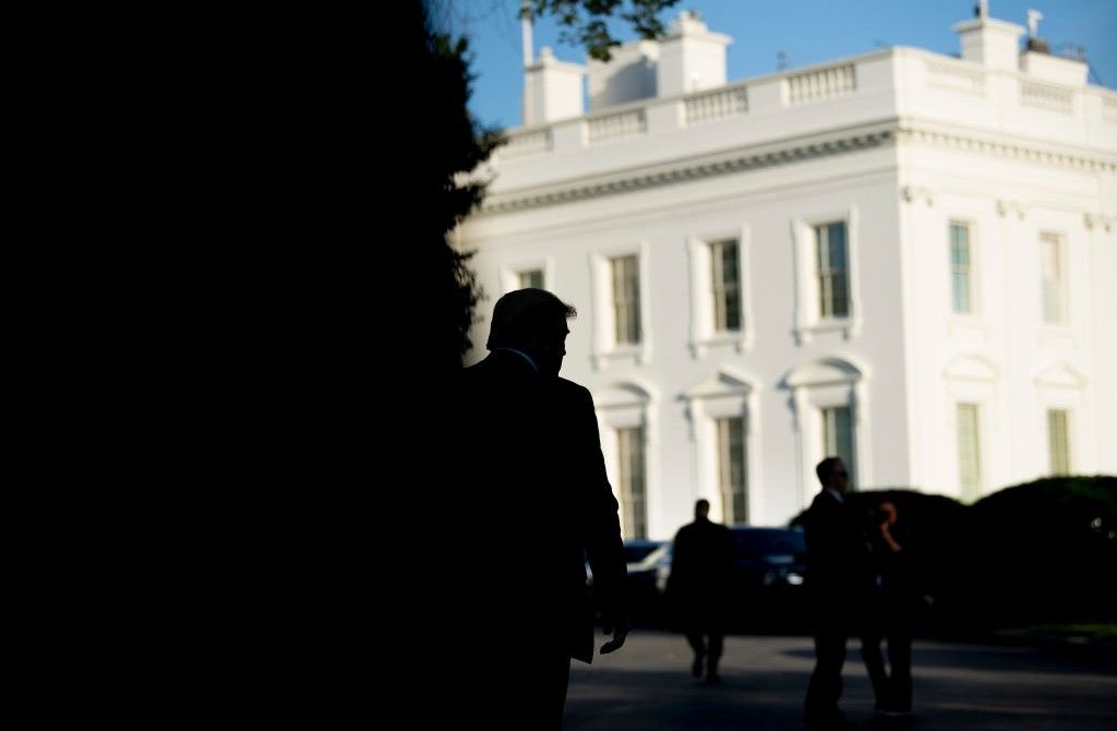 Donald Trump silhouetted against the White House
