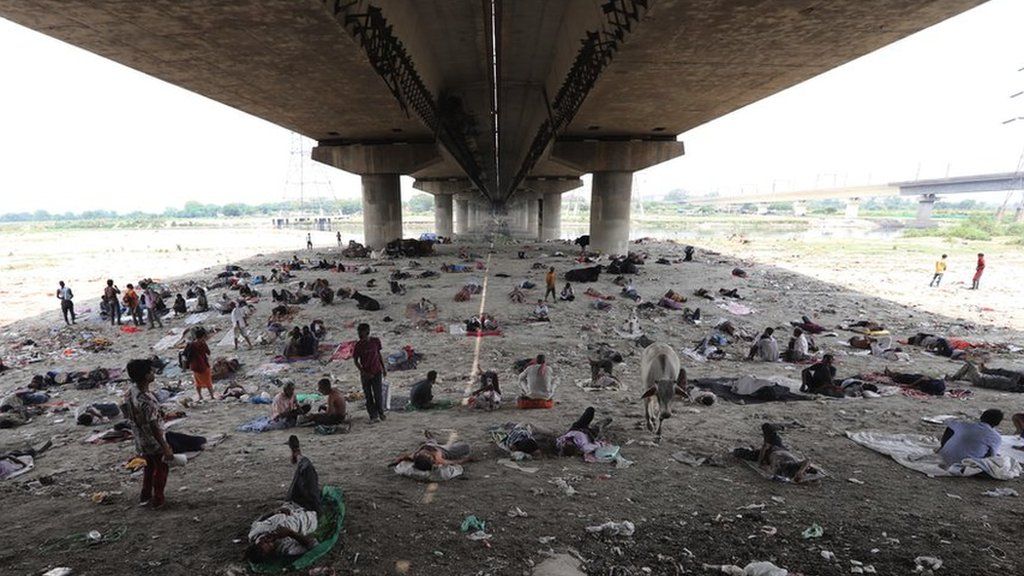 Толпа людей под мостом, укрывающимся от жары.