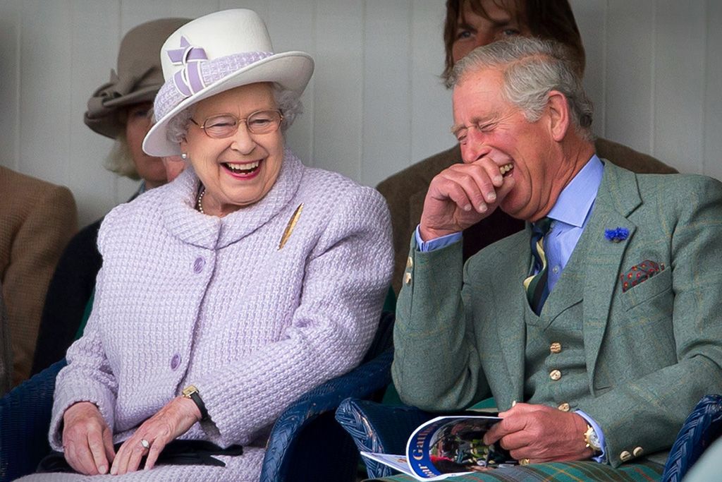 Queen Elizabeth II and Prince Charles laugh whilst watching the children's sack race at the 2012 Braemar Highland Gathering