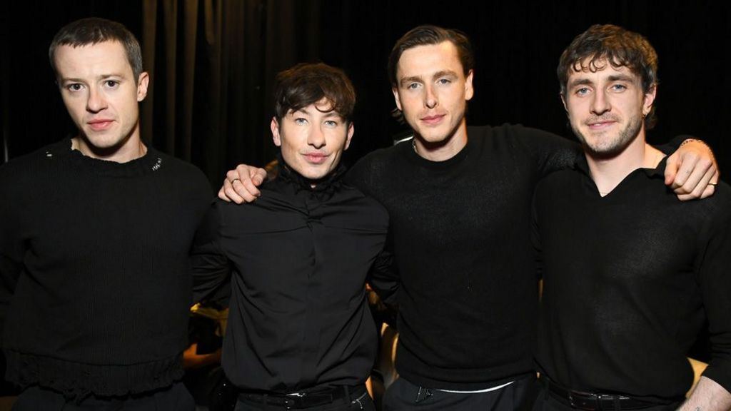 Joseph Quinn, Barry Keoghan, Harris Dickinson and Paul Mescal standing in a line with their arms around each other's shoulders, all dressed in black, at CinemaCon