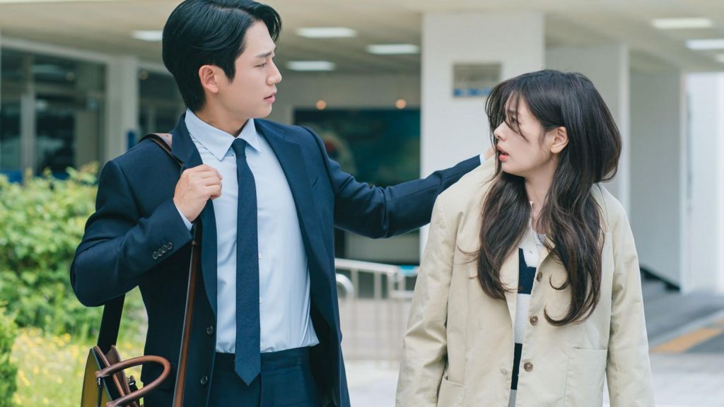 A scene from the K-drama, Love Next Door, where the male lead grabs the coat of the female lead, while they both are walking down a street 