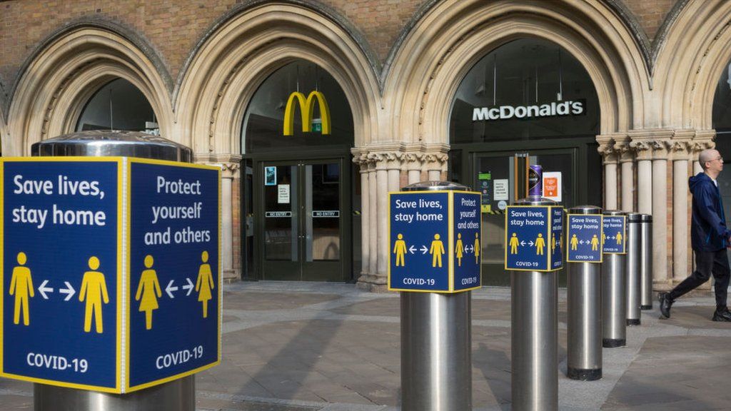 A man walks past the McDonald's restaurant in Liverpool Street Station, with social distancing signs outside
