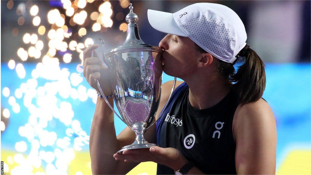 Iga Swiatek kisses the WTA finals trophy