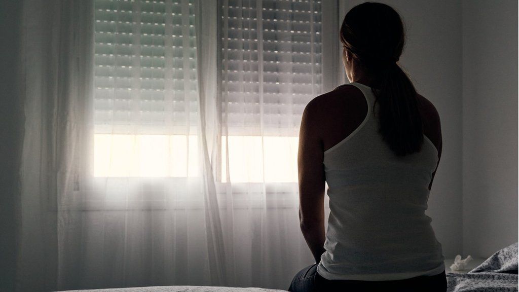 woman sits alone opposite window