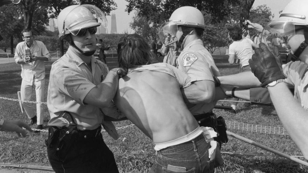 Cigar-smoking officers arresting a protester during a 1968 riot at the DNC. 