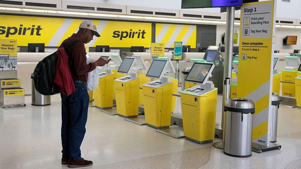  A man wearing a red top and navy trousers and a backpack prepares to check in for his Spirit Airlines flight to Tampa before realising it was cancelled at the Fort Lauderdale-Hollywood International Airport