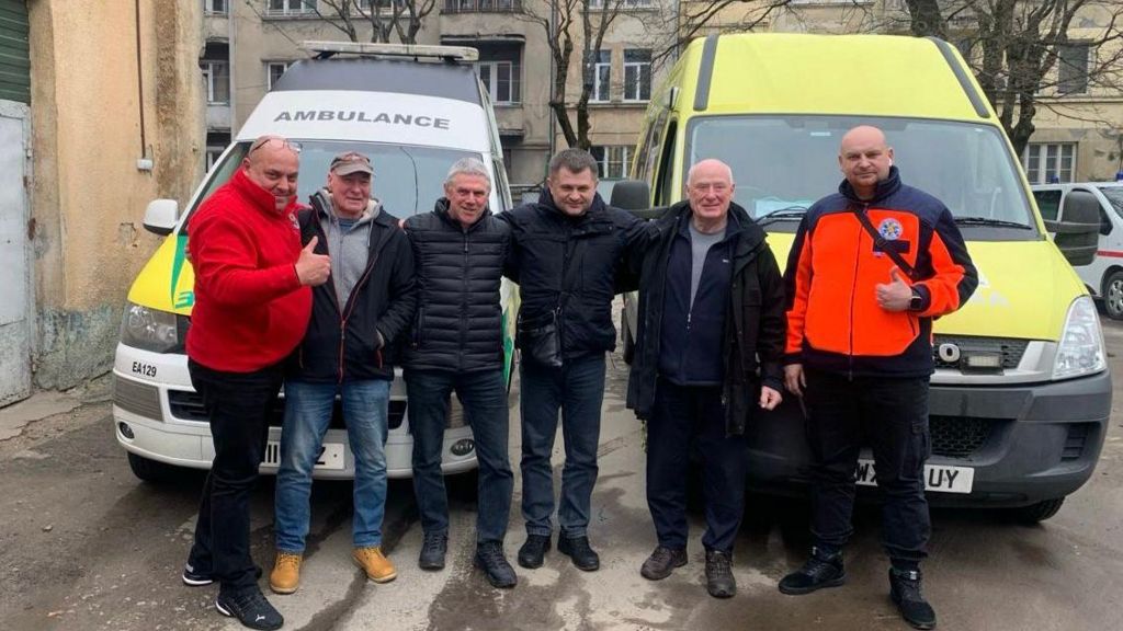 The Pot Place team in Ukraine with two ambulances and a residential building in the background