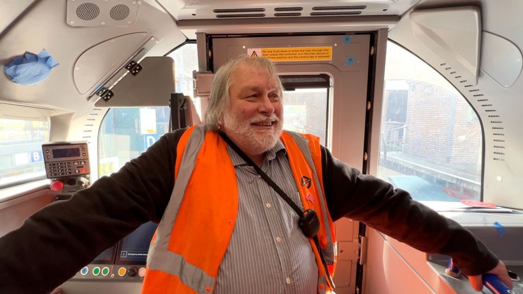 An engineer in hiviz stands in the driver cab