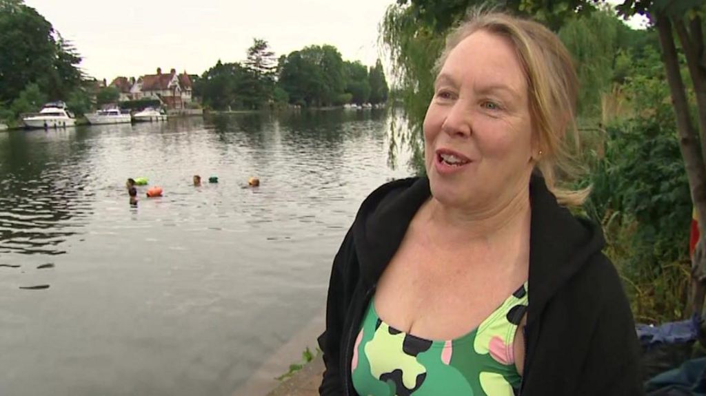 Marlene Lawrence, founder of swimming group, the Teddington Bluetits, being interviewed by the BBC while standing next to the River Thames