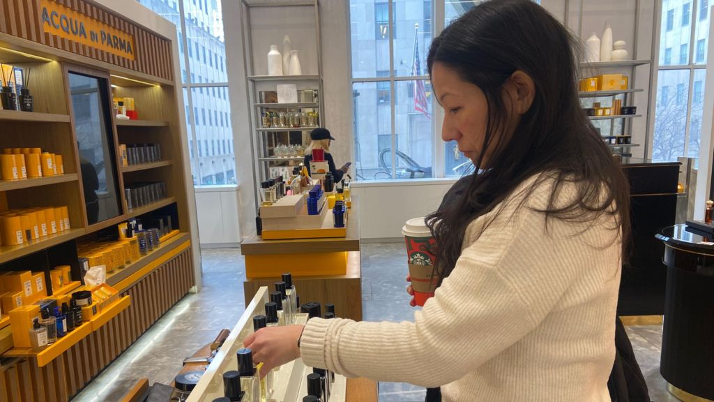 A woman examines fragrance bottles at a department store.