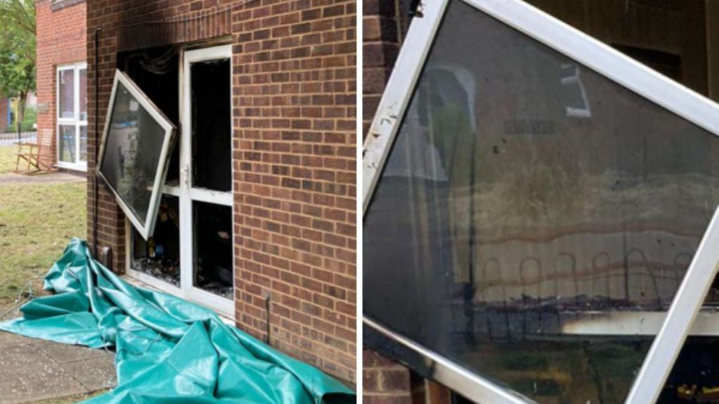 A photograph showing the outside of a flat with a broken glass door damaged by fire. Smoke can be seen on the wall and a window pane is hanging off the door