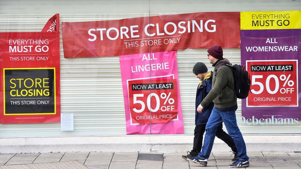 People walk by closed Debenhams shop