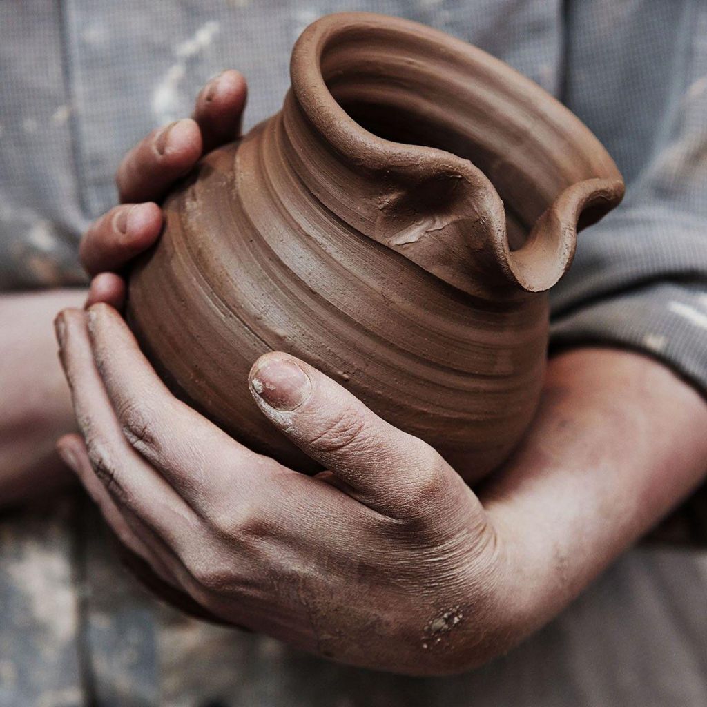 Image of a pottery worker holding a pot